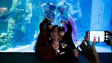 Visitors wearing masks pose for photographs with divers in Korean traditional costumes Hanbok during an event to celebrate New Year. (Reuters)