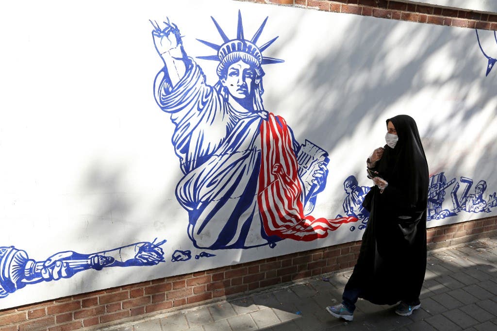A woman, wearing a protective mask amid the COVID-19 pandemic, walks past a mural painted on the outer walls of the former US embassy in the Iranian capital Tehran on September 20, 2020. (AFP)