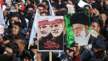 Iraqi demonstrators lift a placards depicting Iraqi commander Abu Mahdi al-Muhandis (C) and Iranian Revolutionary Guards commander Qasem Soleimani (L) and Iran's Supreme Leader Ayatollah Ali Khamenei (R), in Tahrir square in the capital Baghdad on January 3, 2021. (AFP)