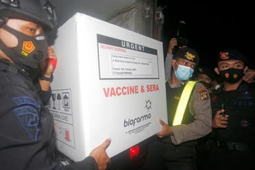 Indonesian security officers carry a box containing coronavirus vaccines upon its arrival in Bali, Indonesia. (AP)