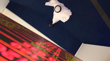 An Emirati trader passes under the stocks display screen at the Dubai Financial Market in Dubai, United Arab Emirates on March 8, 2020. (AP)