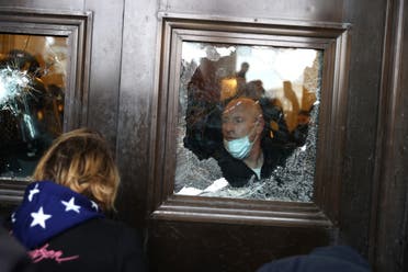  Capitol police officer looks oout of a broken window as protesters gather on the U.S. Capitol Building on January 06, 2021 in Washington, DC. (AFP)