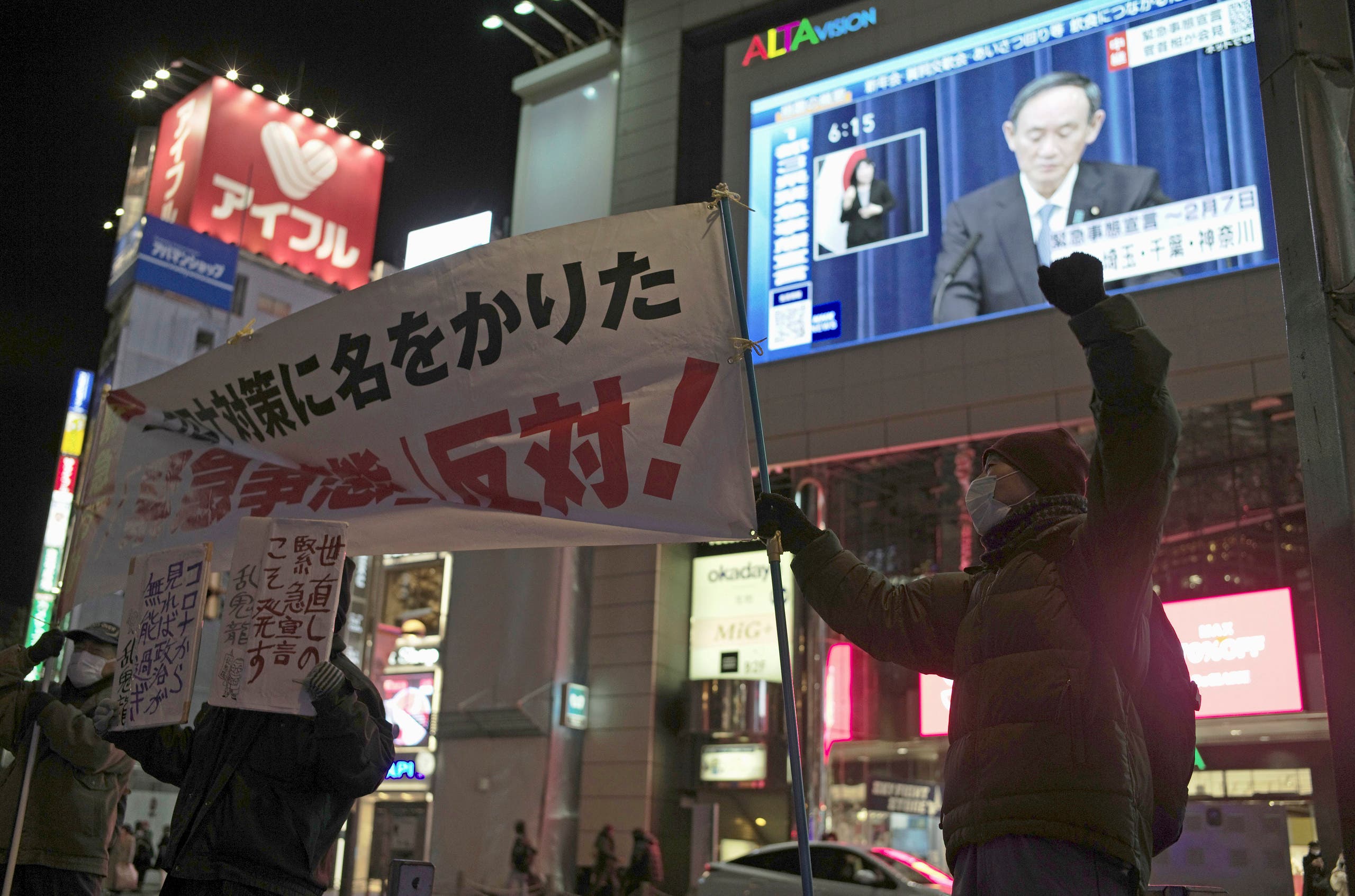 Protesters chant slogans against a state of emergency as Japanese Prime Minister Yoshihide Suga shown on a billboard screen speaks of a state of emergency in Tokyo on Thursday, Jan. 7, 2021.(AP)