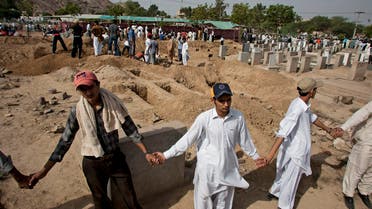 People from a minority Muslim Ahmadi Community stand guard as others preparing to bury the victims of attack by militants, in Rubwah, Pakistan. (AP)