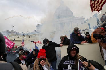 Supporters of President Trump cover their faces to protect from tear gas during a clash with police officers in front of the US Capitol Building in Washington, US, January 6, 2021. (Reuters)