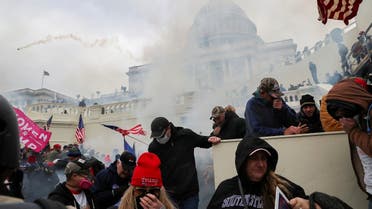 Supporters of President Trump cover their faces to protect from tear gas during a clash with police officers in front of the US Capitol Building in Washington, US, January 6, 2021. (Reuters)