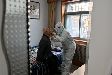 A medical worker in protective suit collects a swab from an elderly man during a door-to-door nucleic acid sampling following a recent coronavirus outbreak in Shijiazhuang, Hebei province, China, on January 7, 2021. (Reuters)