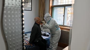 A medical worker in protective suit collects a swab from an elderly man during a door-to-door nucleic acid sampling following a recent coronavirus outbreak in Shijiazhuang, Hebei province, China, on January 7, 2021. (Reuters)