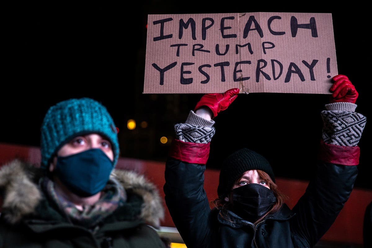 A woman wearing a protective mask holds a sign during the Get him out! defend democracy rally, a day after supporters of U.S. President Donald Trump stormed the Capitol, in the Brooklyn borough of New York City, New York, U.S., January 7, 2021. (Reuters)