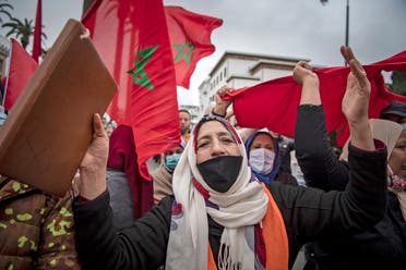 Moroccans celebrate in front of the parliament building in Rabat on December 13, 2020, after the US adopted a new official map of Morocco that includes the disputed territory of Western Sahara. (AFP)