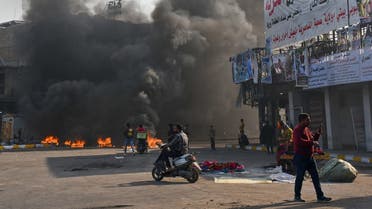 Iraqi protesters are pictured next to burning tires during clashes with police during anti-government demonstrations in the city of Nasiriyah in the Dhi Qar province in southern Iraq on January 10, 2021. (Asaad Niazi/AFP)