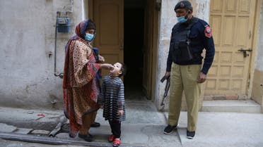 A police officer stand guard while a healthcare worker administers a polio vaccine to a child in Peshawar, Pakistan, on January 11, 2021. (AP)