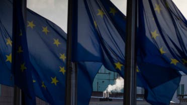 Smoke rises from a chimney behind EU flags fluttering in the wind outside EU headquarters in Brussels, Belgium. (AP)