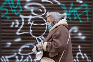 A woman wearing a face mask to protect against coronavirus walks past a closed shop in Ivano-Frankivsk, Western Ukraine. (AP)