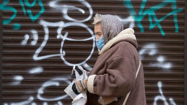 A woman wearing a face mask to protect against coronavirus walks past a closed shop in Ivano-Frankivsk, Western Ukraine. (AP)
