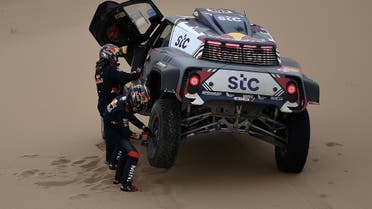 Mini's driver Stephane Peterhansel and his co-driver Edouard Boulanger of France change a tire as they compete during the Stage 11 of the Dakar 2020 between Alula and Yanbu, Saudi Arabia. (AFP)