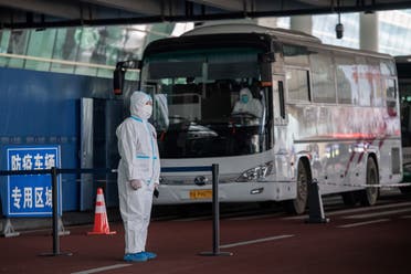 Health workers stand next to buses at a cordoned-off section at the international arrivals area. (AFP)