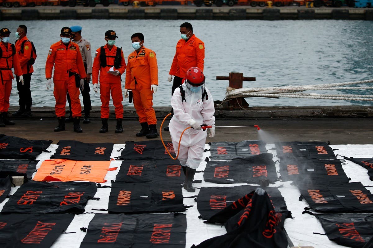 An Indonesian Red Cross worker sprays disinfectant on bags containing body parts of passengers of the Sriwijaya Air flight SJ 182, which crashed into the Java sea, at Tanjung Priok port in Jakarta, Indonesia, on January 14, 2021. (Reuters)