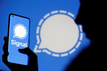 A woman holds a smartphone displaying the Signal messaging app logo, which is also seen near her, in this illustration taken January 13, 2021. (Reuters)