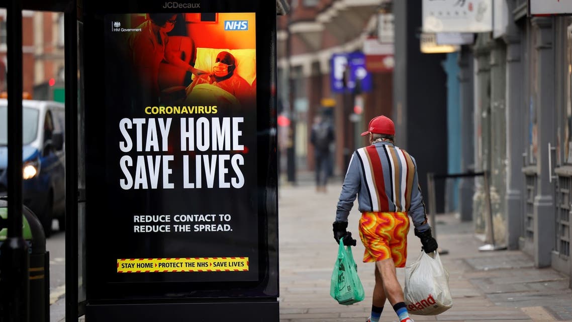 A shopper walks past NHS signage promoting Stay Home, Save Lives on a bus shelter in Chinatown, central London. (AFP)