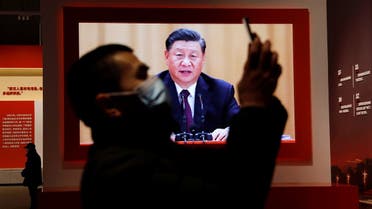 A visitor holds his mobile phone near a screen showing Chinese President Xi Jinping. (Reuters)