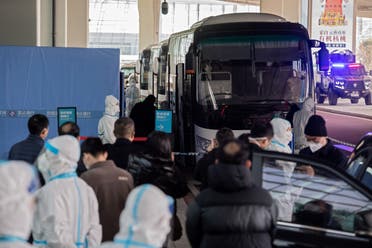 Members of the World Health Organization (WHO) team investigating the origins of the Covid-19 pandemic board a bus following their arrival at a cordoned-off section in the international arrivals area at the airport in Wuhan. (AFP)