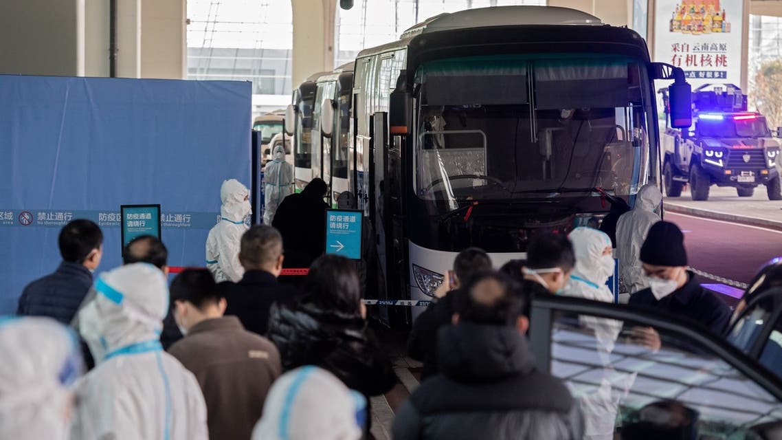 Members of the World Health Organization (WHO) team investigating the origins of the Covid-19 pandemic board a bus following their arrival at a cordoned-off section in the international arrivals area at the airport in Wuhan. (AFP)