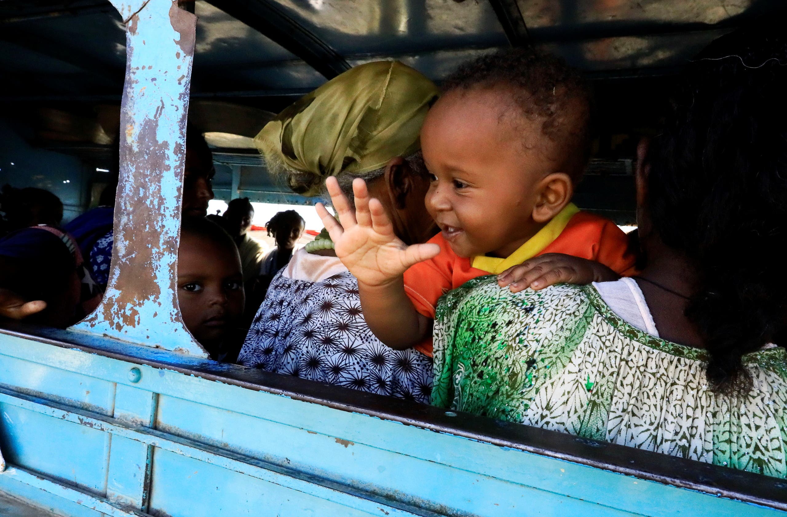 An Ethiopian refugee who fled Tigray region holds a child inside a courtesy bus at the Fashaga camp, as they are transferred to Um-Rakoba camp on the Sudan-Ethiopia border, in Kassala state, Sudan. (Reuters)