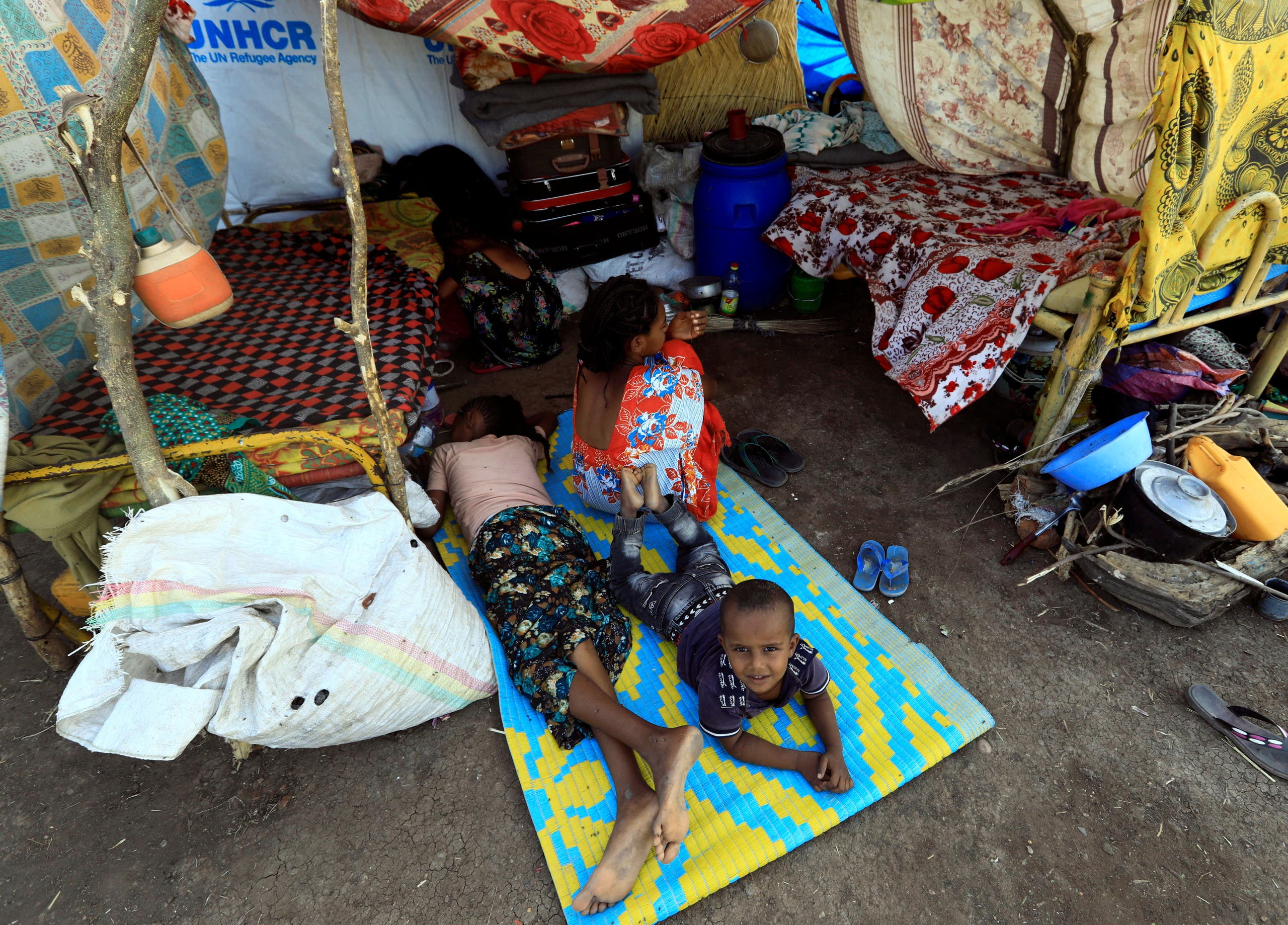 Ethiopians who fled the ongoing fighting in Tigray region, sit and lay in their makeshift shelter in the Hamdayet village, in eastern Kassala state, Sudan. (Reuters)