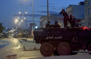 Members of the Tunisian National Guard sit atop their armoured vehicle, stationed on a street amid clashes with demonstrators following a protest in the Ettadhamen neighbourhood in the capital Tunis, on January 17, 2021. (AFP)