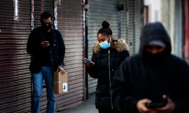 People look at their mobile phones as they walk past closed shops in London on Jan. 16, 2021. (AP)