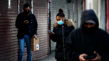 People look at their mobile phones as they walk past closed shops in London on Jan. 16, 2021. (AP)