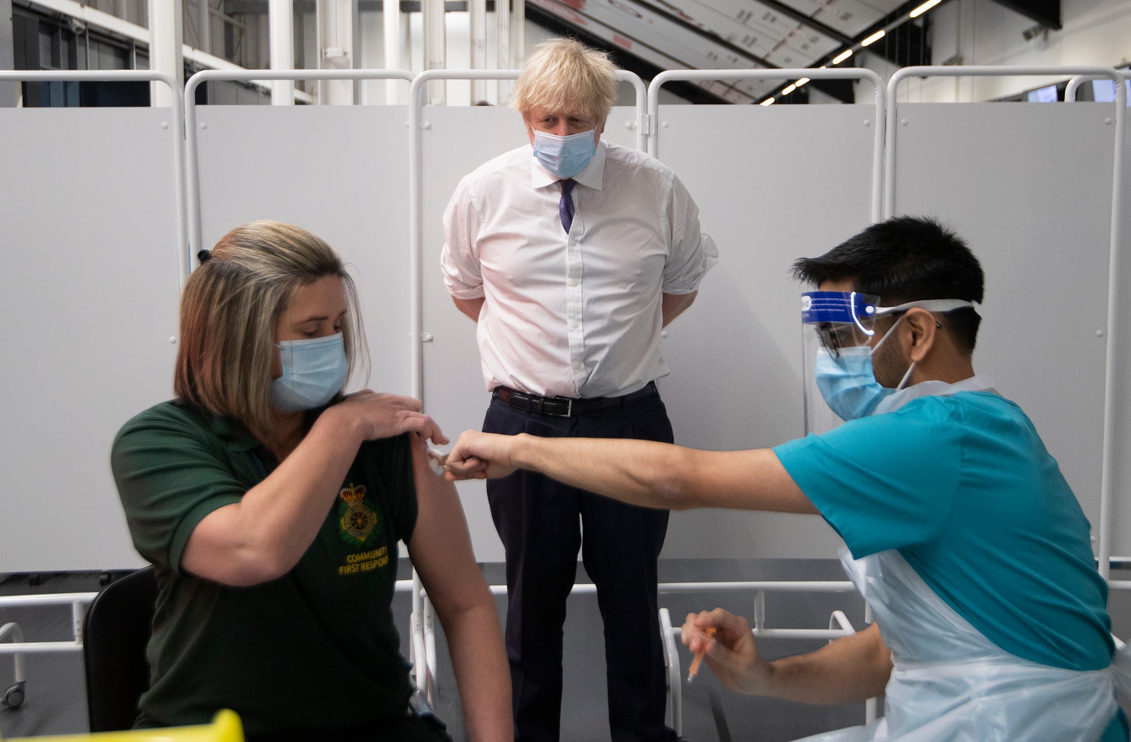 Britain's Prime Minister Boris Johnson watches first responder Caroline Cook receiving an injection of a Covid-19 vaccine at Ashton Gate Stadium in Bristol, England on Jan. 11, 2021. (AP)