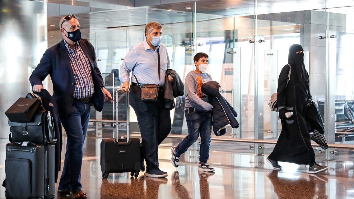 Mask-clad travelers walk with their carry-on luggage to board the first Qatar Airways flight bound for Cairo after the resumption of flights between Qatar and Egypt, at Qatar's Hamad International Airport near the capital Doha on January 18, 2021. (Karim Jaafar/AFP)