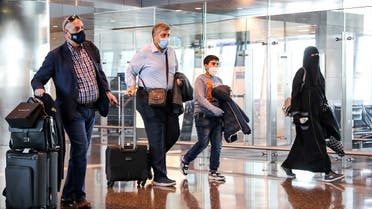 Mask-clad travelers walk with their carry-on luggage to board the first Qatar Airways flight bound for Cairo after the resumption of flights between Qatar and Egypt, at Qatar's Hamad International Airport near the capital Doha on January 18, 2021. (Karim Jaafar/AFP)