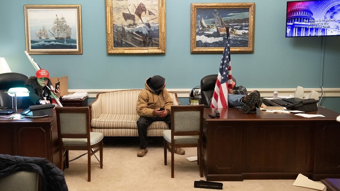 Supporters of US President Donald Trump sit at desks in the office suite of Speaker of the House Nancy Pelosi after breaching the US Capitol in Washington, DC, January 6, 2021. (Saul Loeb/AFP)