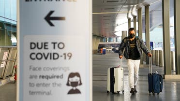 A sign displaying COVID-19 prevention protocols stands beside the passenger drop-off area as travelers arrive at Terminal C at LaGuardia Airport. (AP)
