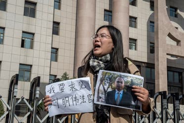Xu Yan, wife of human rights lawyer Yu Wensheng, holding a piece of paper that reads 'I want to request a meeting with Judge Liu Mingwei' and a picture of her husband outside the Xuzhou Intermediate People’s Court in Xuzhou on October 31, 2019. (AFP)
