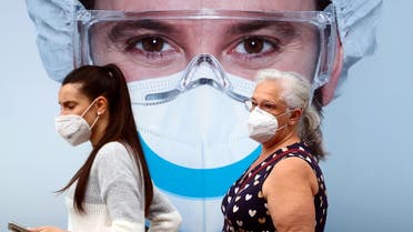 People, wearing protective face masks, walk past a dental clinic advertisement at Vallecas neighbourhood in Madrid, Spain, on September 18, 2020. (Reuters)