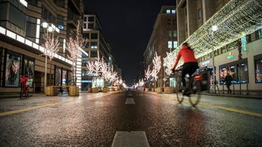 A lone cyclist rides past closed shops on illuminated and empty Friedrichstrasse in Berlin amid the COVID-19 pandemic. (AFP)