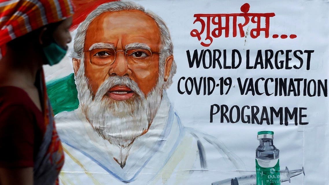 A woman walks past a painting of Indian Prime Minister Narendra Modi a day before the inauguration of the COVID-19 vaccination drive on a street in Mumbai, India, on January 15, 2021. (Reuters)