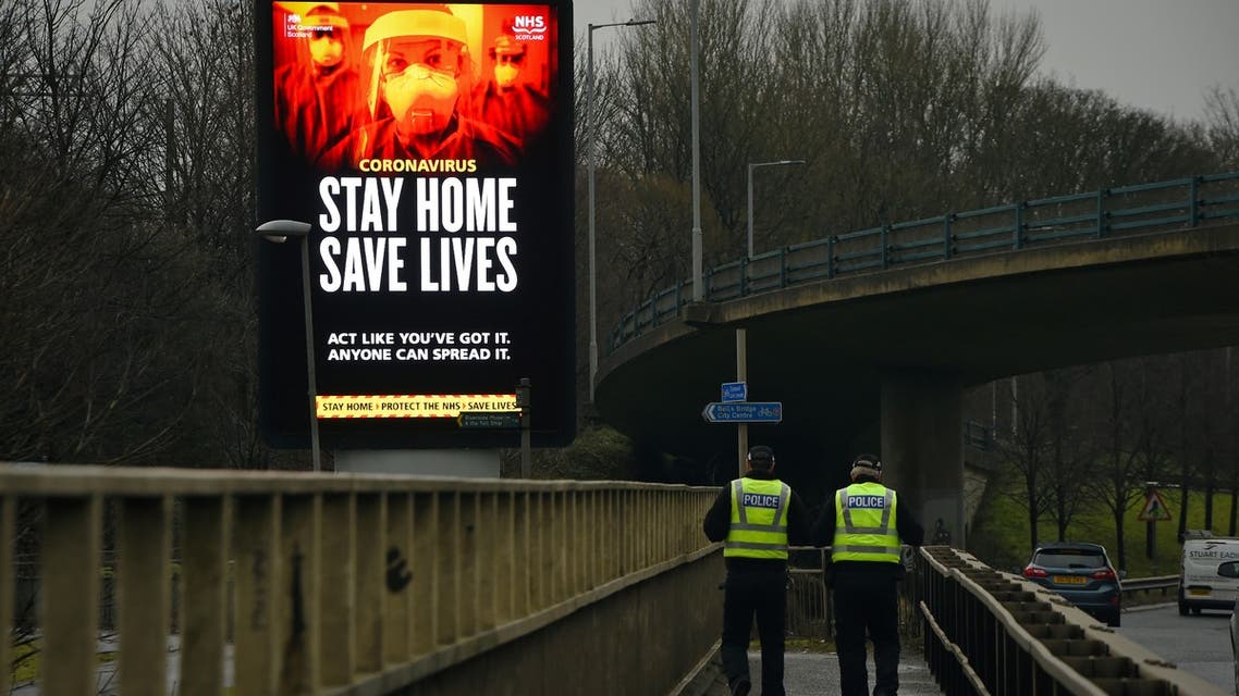 Police officers walk past a Covid-19 information board alongside the Clydeside Expressway in Glasgow, UK. (AFP)