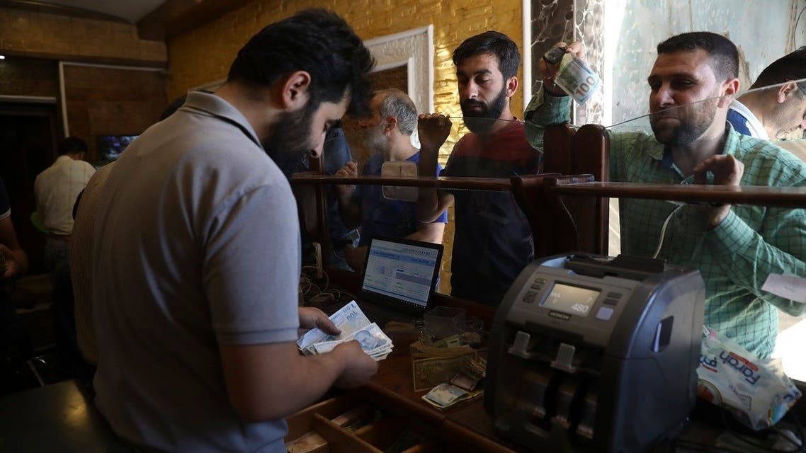 People exchange money in the city of Idlib, Syria, June 20, 2020. (AP Photo/Ghaith Alsayed)