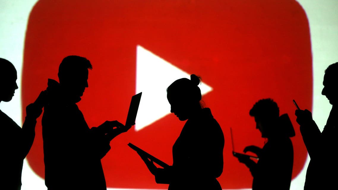 FILE PHOTO: Silhouettes of laptop and mobile device users are seen next to a screen projection of the YouTube logo in this picture illustration taken March 28, 2018. REUTERS/Dado Ruvic/Illustration/File Photo
