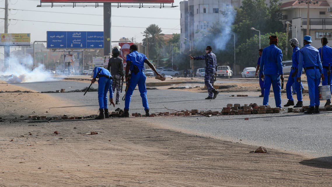 Members of Sudanese security forces remove obstacles placed by protesters as tear gas fumes billow during a demonstration against rising prices, on the main al-Sittin (sixty) road in the capital Khartoum, on January 24, 2021.