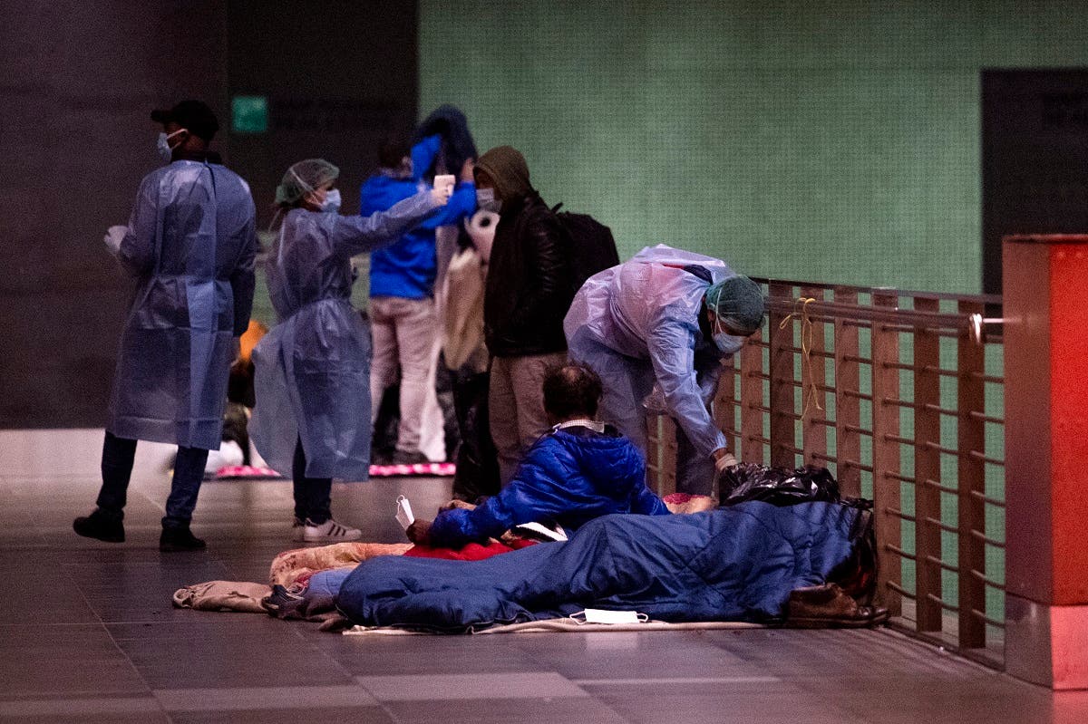 A doctor (Rear R) from MEDU organization (Doctors for Human Rights) performs a temperature scanning on a homeless man (Bottom Front) as doctors roam across the Tiburtina train station on November 25, 2020 in Rome, as part of a MEDU mobile team series of free health checks. (Tiziana Fabi/AFP)