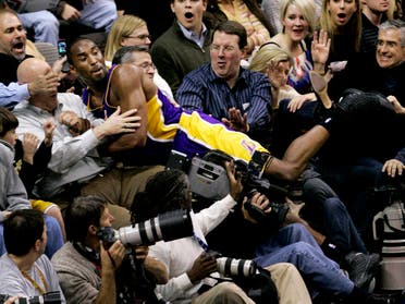 Kobe Bryant lands amongst fans after chasing down a loose ball in the second half of an NBA basketball game against the Dallas Mavericks in Dallas, Friday, Jan. 25, 2008. (AP)