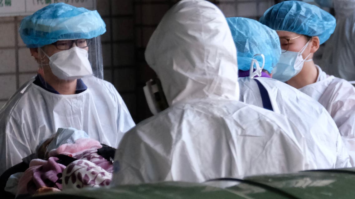 Masked medical staff escort a patient outside the Taoyuan General Hospital, where a cluster of Covid-19 coronavirus infections were detected. (AFP)