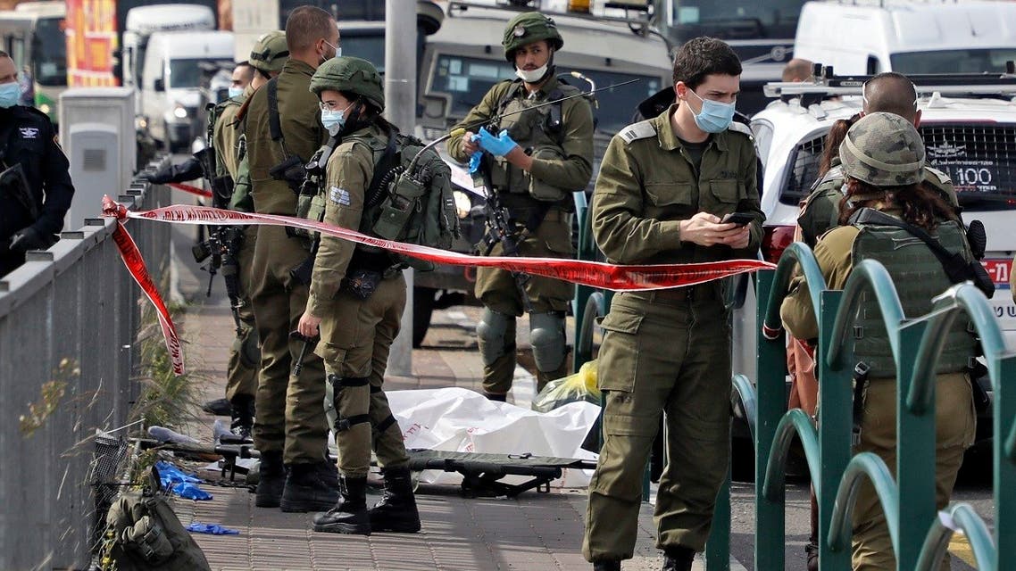 Israeli soldiers gather by the body of the alleged Palestinian attacker who was shot dead at the Gitai Avisar Junction, west of the Jewish settlement of Ariel and south of Nablus in the occupied West Bank, January 26, 2021. (Jaafar Ashtiyeh/AFP)