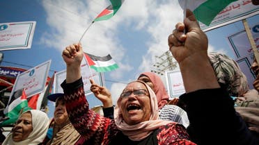 Palestinian women lift national flags and placards during a rally for supporters of the Fateh movement against Israel's West Bank annexation plans, in Beit Hanun in the north of the Gaza Strip, July 6, 2020. (AFP)